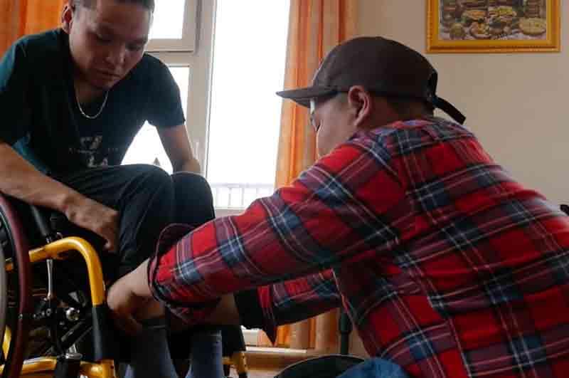 Ragazzo disabile viene aiutato a vestirsi in Mongolia