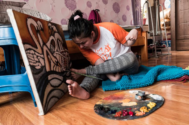 Ragazza disabile in Mongolia dipinge con i piedi